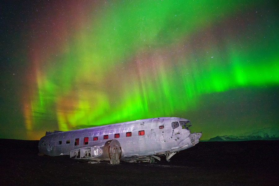 Islande, Solheimasandur. Carcasse d'un avion écrasé, sous une aurore boréale.